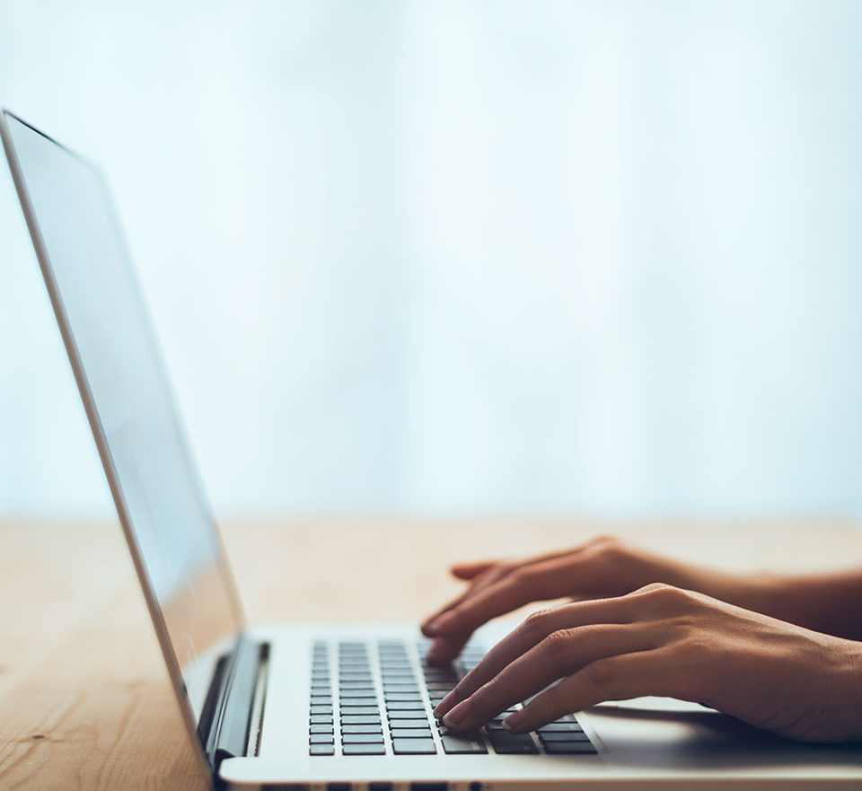 Photo of open laptop with hands of woman typing on keyboard