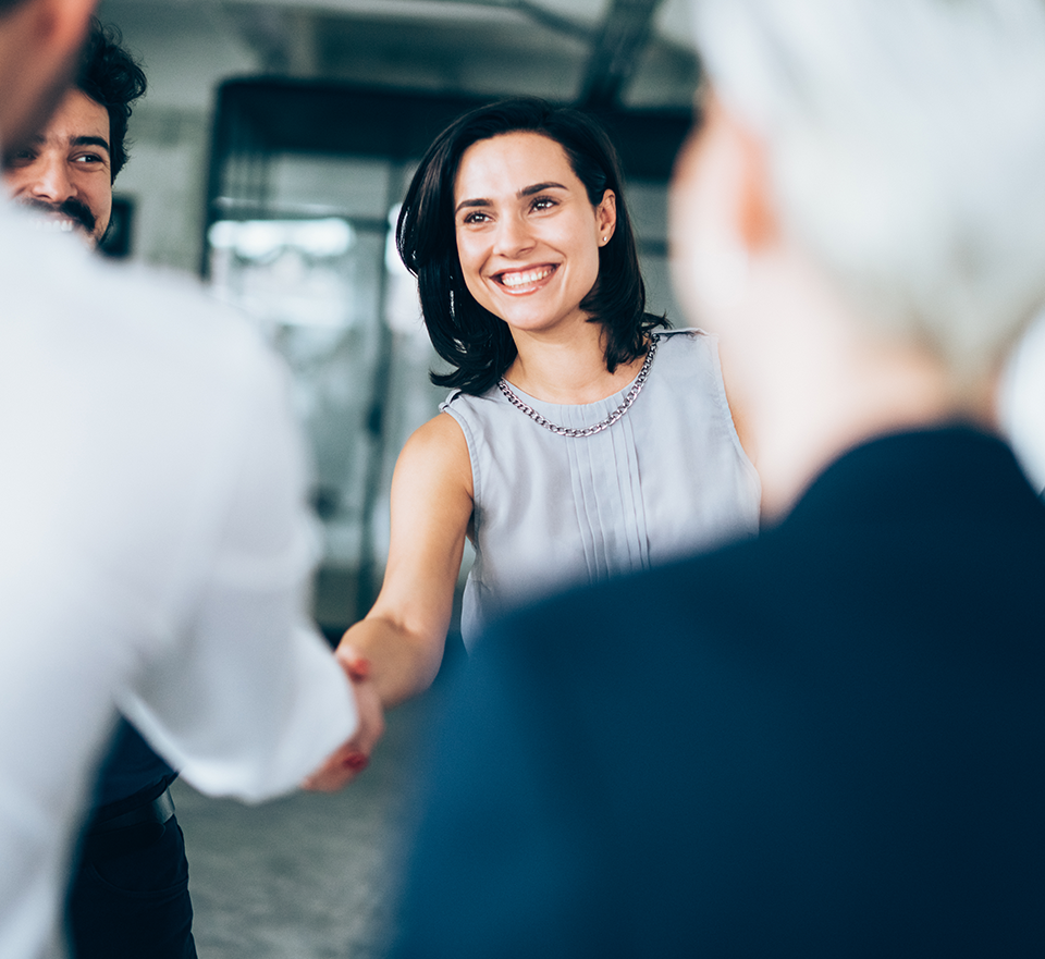 Businesswoman smiling and shaking hands with businessman in meeting